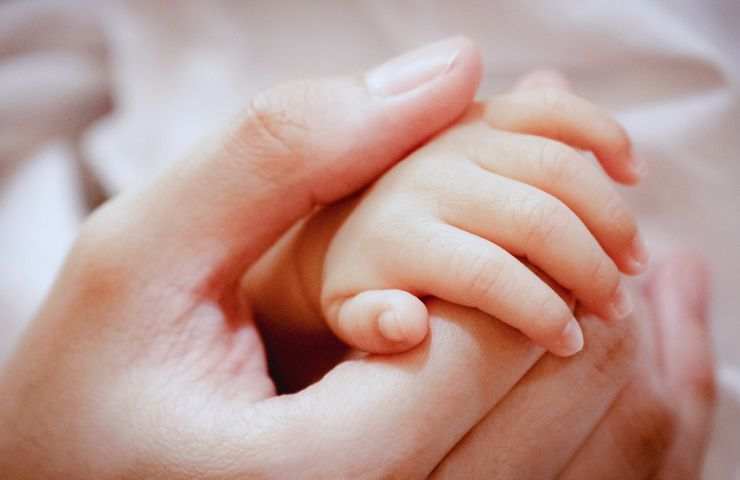 manina neonato e mano mamma