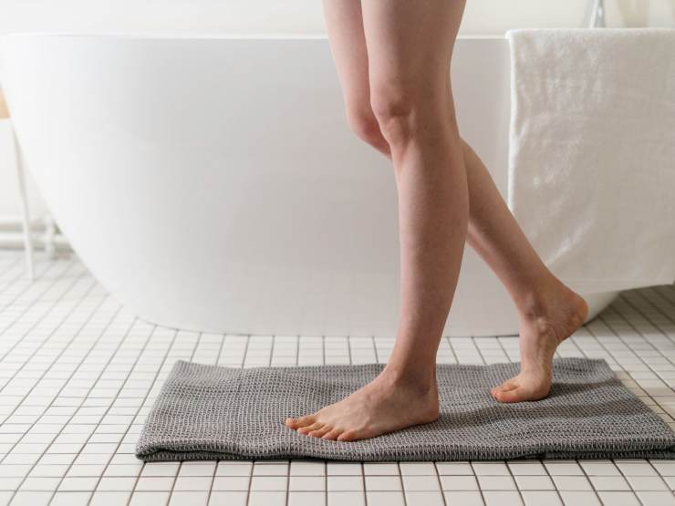 gambe ragazza su tappetino da doccia in bagno