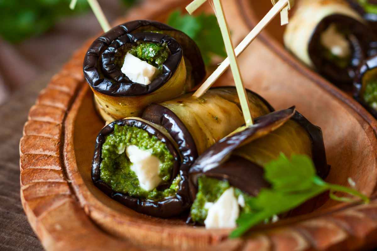 Primo piano di involtini di melanzane e ricotta in una ciotola di legno