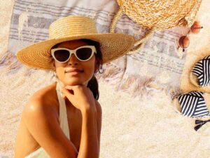 sfondo telo da mare e borsa e donna in costume con cappello di paglia e occhiali