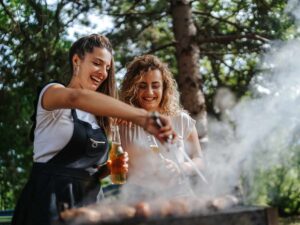Due amiche cuociono la carne sul barbecue