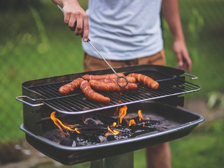Un ragazzo cuoce la carne sul barbecue
