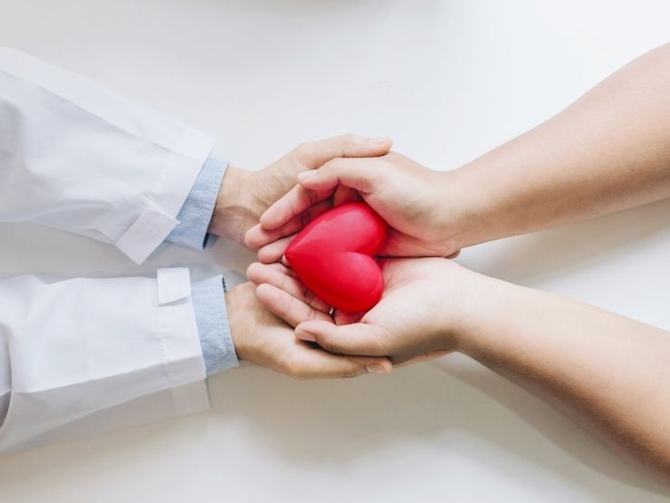 Un cardiologo e una piccola paziente tengono in mano un cuoricino rosso