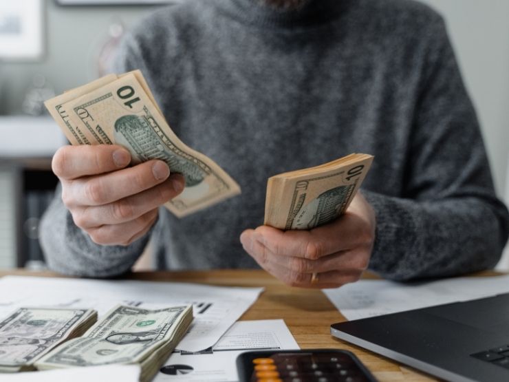 Persona seduta alla scrivania conta le banconote