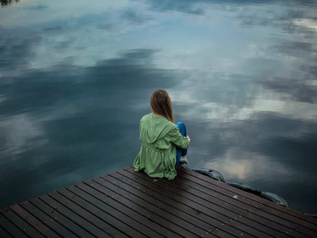 Una ragazza triste guarda un lago