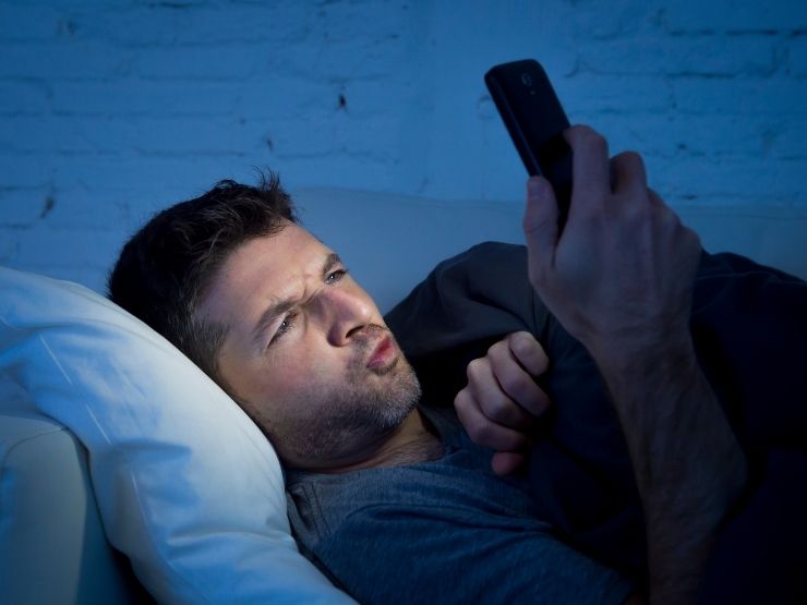 Ragazzo nel letto mentre guarda foto di donne