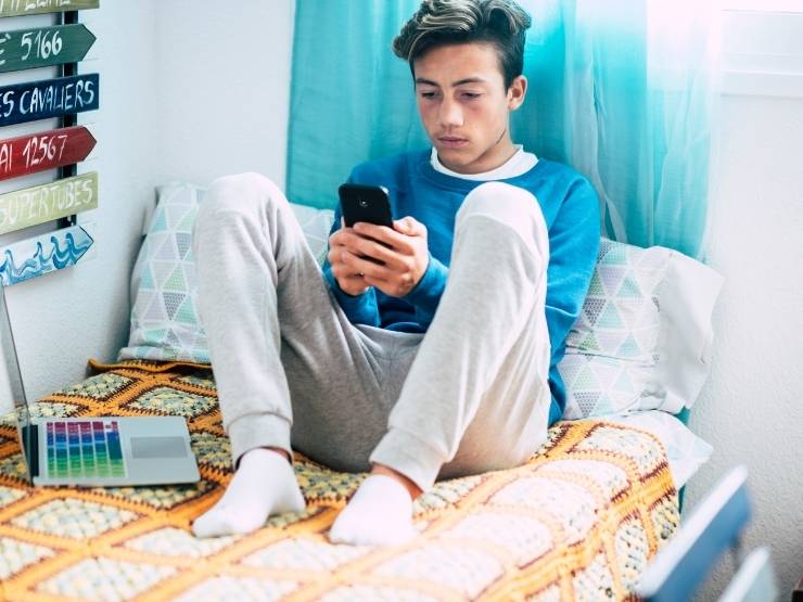 Adolescente sul letto con lo smartphone