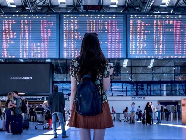 Viaggiatrice guarda il cartellone dei voli in ritardo in aeroporto