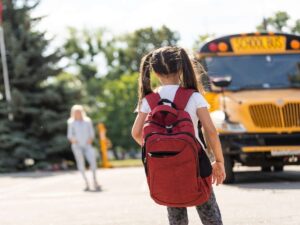 Una bimba con lo zaino in spalla aspetta lo scuolabus