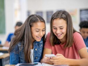 Due studentesse usano il cellulare in classe