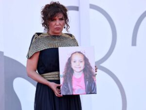 La regista Kaouther Ben Hania con in mano una foto di Hind Rajab a Venezia 82