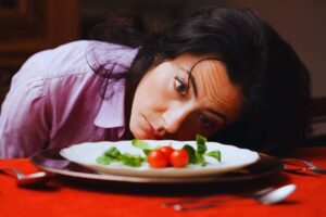 ragazza depressa davanti insalata