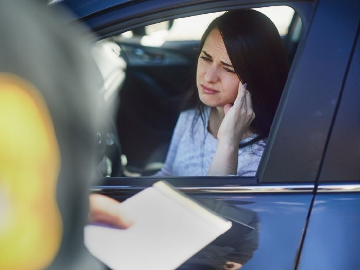 agente che multa donna in auto con viso triste