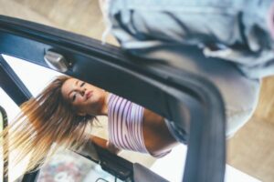 Donna arrampicata sul tettuccio apribile dell'auto