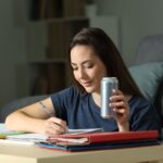 Ragazza beve energy drik mentre studia